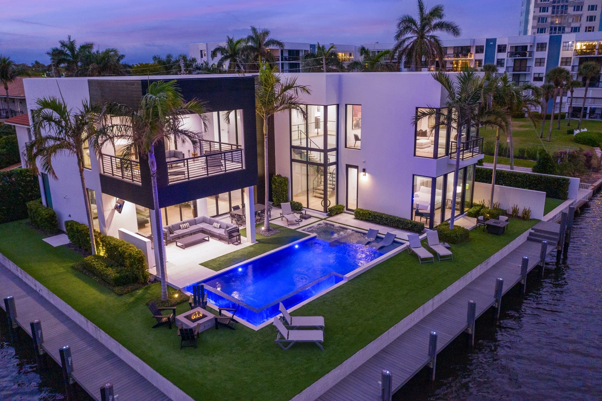 Aerial twilight view of a modern Delray Beach estate with glowing infinity pool from the Intracoastal
